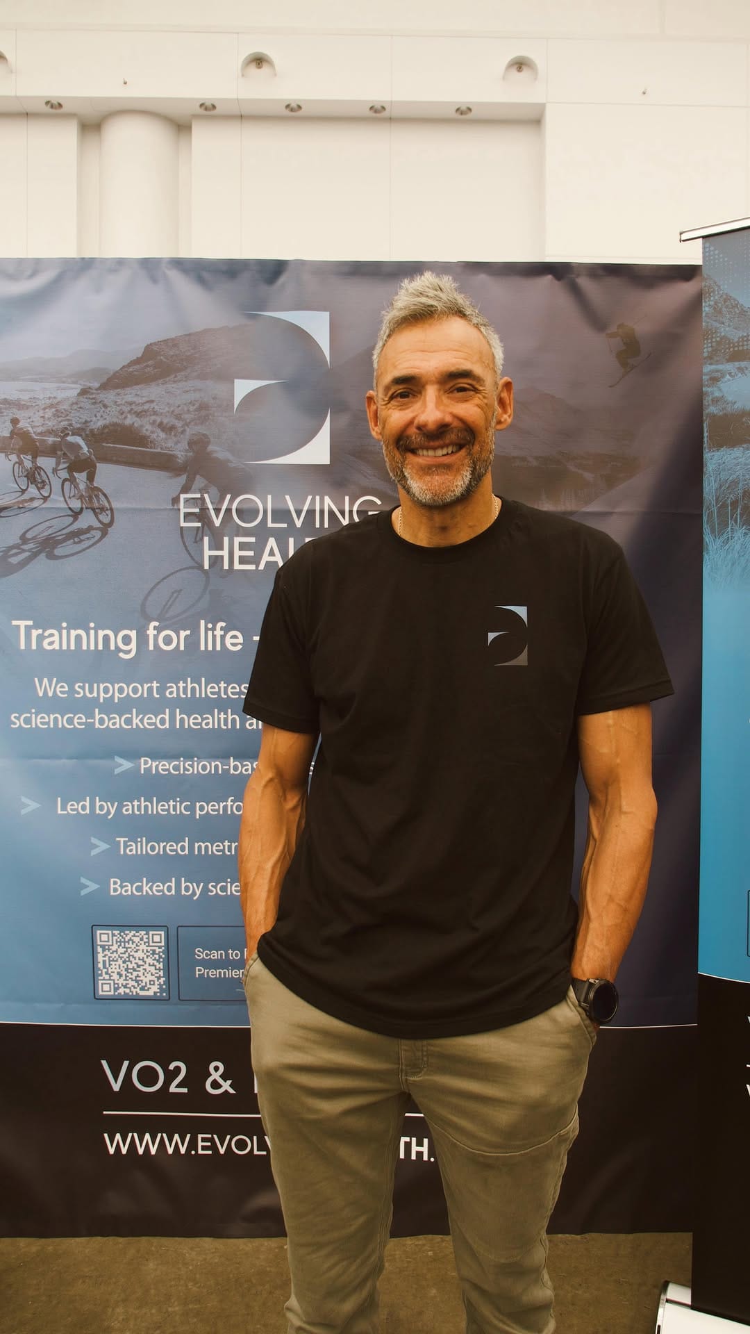 Smiling man standing in front of an Evolving Health banner