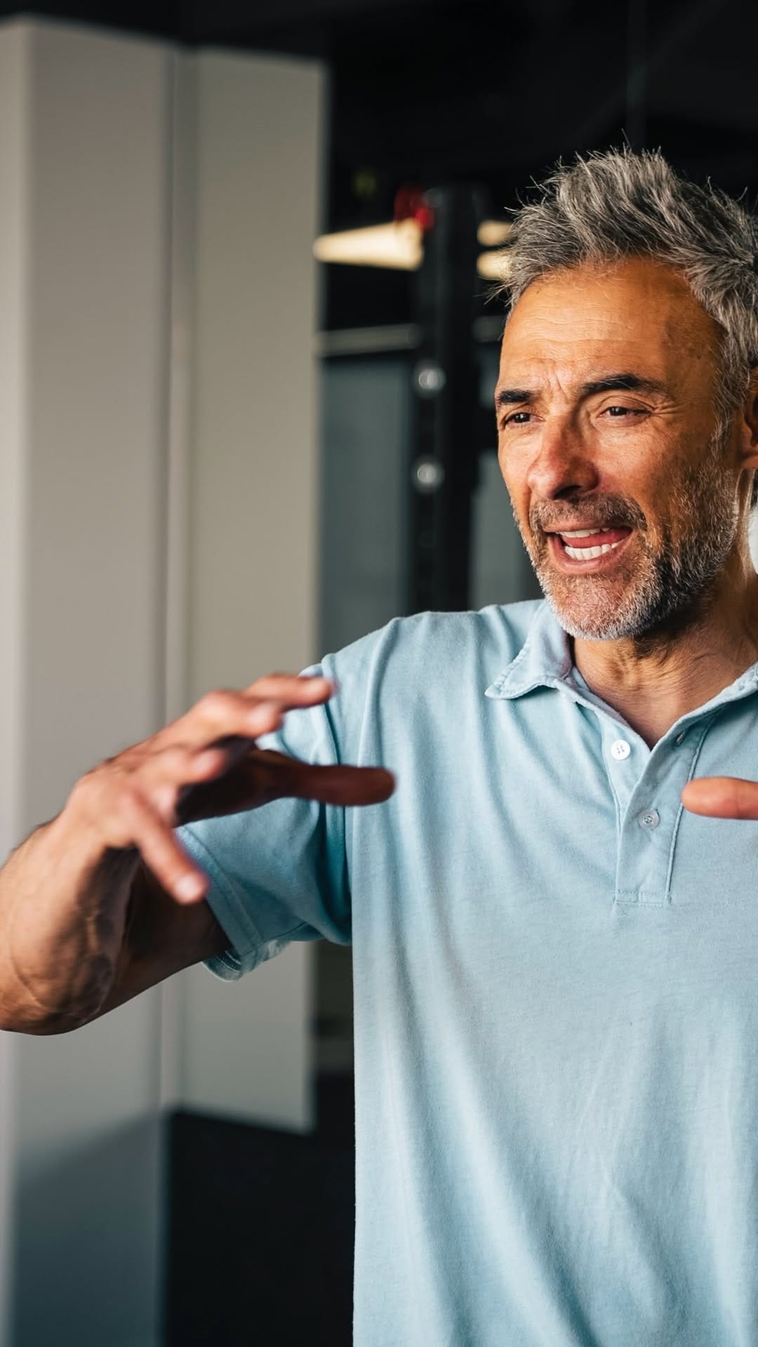 Man in a blue polo gesturing as he speaks in the clinic