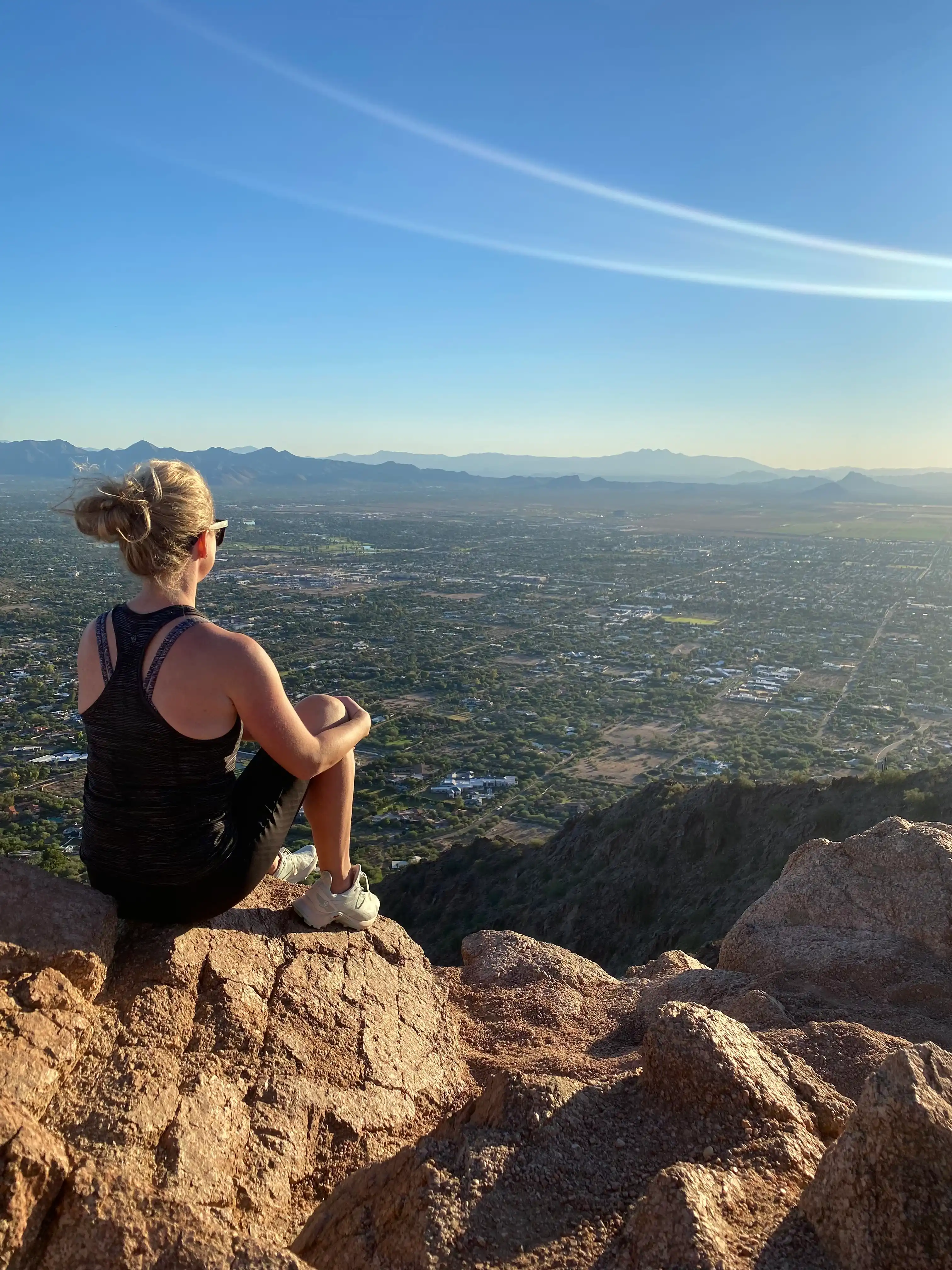 Woman sitting on a rocky ledge looking out over a valley